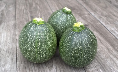 Round courgette on wooden background.