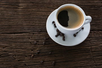 Coffee cup with coffee beans on dark wooden table, black coffee