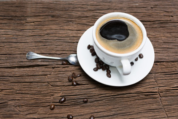 Coffee cup with coffee beans on dark wooden table, black coffee