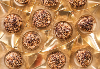 Chocolates sprinkled with crumbs from the wafers in a Golden box,