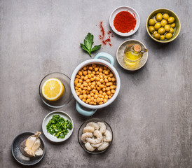 Various cooking ingredients in bowls for Chickpea salad on gray concrete background, top view, copy space. Healthy , clean food or vegetarian cooking and eating concept