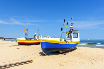 Naklejka premium Kolorowe łodzie rybackie na piaszczystej plaży w Sopocie w słoneczny dzień. Morze Bałtyckie, Pomorze. Polska