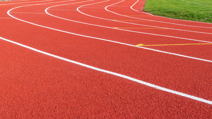 Red running track and white lanes on sport stadium