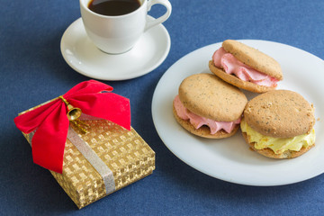 Coffee with cakes, Christmas toys and a box with a gift on denim. Christmas composition.