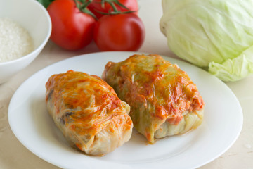 Cabbage rolls on a white plate and ingredients. Tasty dish.