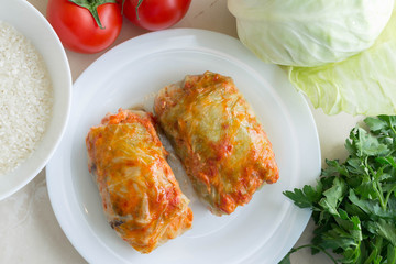 Cabbage rolls on a white plate and ingredients. Tasty dish.