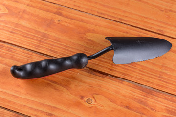 Unused black metal garden shovel on the wooden planks background