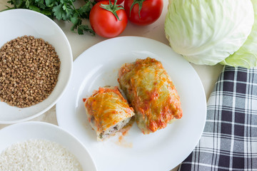 Cabbage rolls on a white plate and ingredients. Tasty dish.