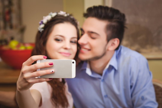 Young enamored couple sitting at a table in a cafe and making selfie