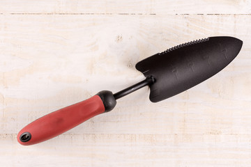 Unused garden shovel in the hand above wooden background