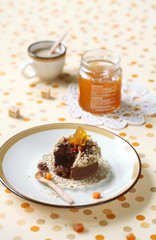 Chocolate Financier Cake (broken) with Apricots and Streusel Topping on plate, cup of coffee and pot of jam, on bright polka dotted background.