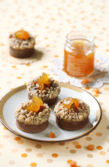 Chocolate Financier Cakes with Apricots and Streusel Topping on plate, on bright polka dotted background.