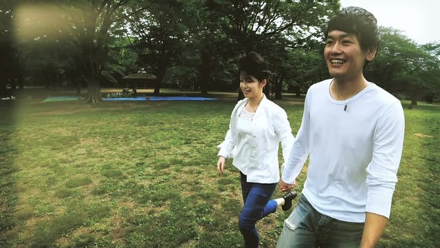 カップル男女手をつなぎ　公園を走る　ジンバル移動撮影　グレーディング　フレア逆光調