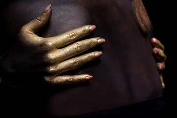 golden hands in dark back, beauty and body paint concept