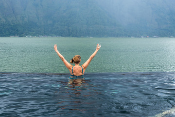 Senior woman in the nature swimming pool with amazing mountain background. Tropical island Bali, Indonesia.