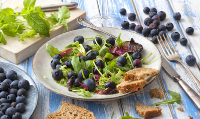 Healthy salad with rocket and blueberries on an outdoor table.