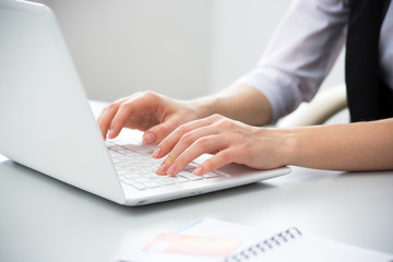 Close-up of hands of businesswoman typing on a laptop.