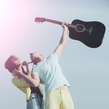 Pretty woman singing to mic with handsome man with guitar