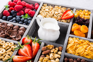 Old gray wooden box with variety of cold quick breakfast cereals and berries for breakfast, healthy eating concept, selective focus.