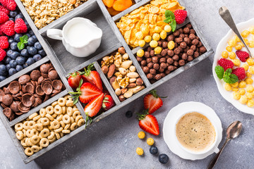 Healthy breakfast with coffee, variety of cold quick cereals and berries in old gray wooden box, top view.