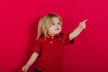 small happy boy pointing finger on pink background