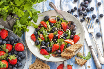 Healthy salad with blueberries, strawberries and rocket on an outdoor table.