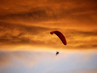 Paramotor flying in the sunset sky, Silhouette shot.