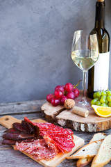 Glass with white wine, grape, cheese, over rustic wooden background. Wine snack set.