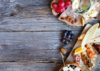 Glass with white wine, grape, cheese, over rustic wooden background. Wine snack set.