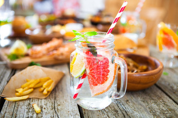 Detox fruit water on wooden table. Fresh homemade lemonade with mint.