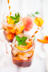 Homemade lemonade with ripe  peaches and fresh mint. Fresh peach ice tea on white wood table. Copy space background.