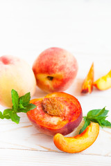 Fresh peaches with mint on wooden white background.