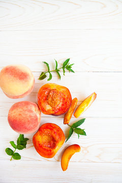 Fresh peaches with mint on wooden white background. Top view, flat lay.