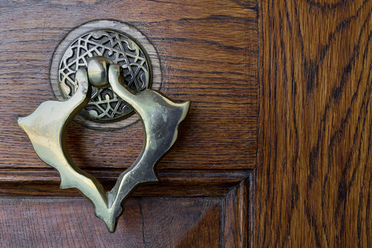 Closeup of antique copper ornate door knocker over an aged wooden door, Fatih Mosque, Istanbul, Turkey