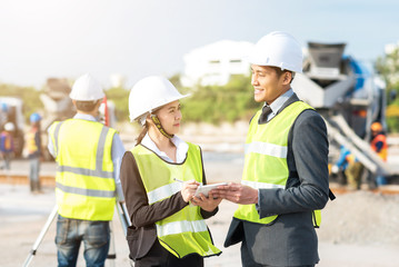 Happy Engineer and secretary discussing about new construction project with worker using altometer at construction site