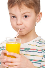 Portrait of happy little boy drinking refreshing orange juice. Smiling child with glass of fresh lemonade.