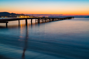 Fototapeta na wymiar Sunset on a sandy beach and a wooden pier, Panorama