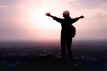 The silhouette of a woman tourist spread his arms wide as a winner or freedom on the landscape, the...