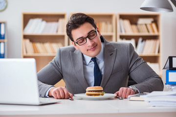 Hungry funny businessman eating junk food sandwich