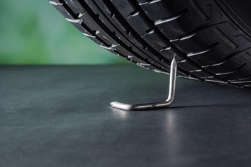Tire spikes with car tire and green nature background at back, Bend and twist sharp steel rod or...