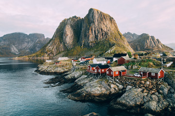 Lofoten islands is an archipelago in the county of Nordland, Norway. Distinctive scenery with dramatic mountains and peaks, open sea and sheltered bays and red fishing huts, called rorbu. - obrazy, fototapety, plakaty