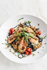gourmet grilled prawn and vegetables on black squid ink pasta