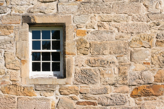 old style paned glass window set in stone wall