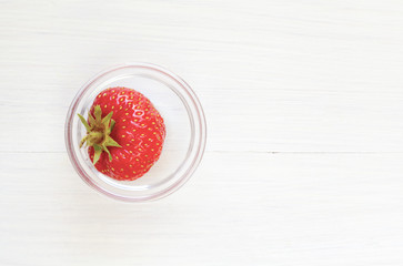 Single strawberry in tiny glass bowl