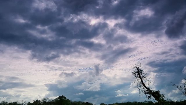 Dark clouds on a background of a bright sky. Rapid movement of clouds across the sky.