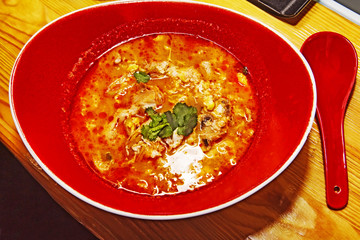 Tom Yam traditional Thai Soup served on a red serving plate