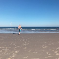 парень идет по пляжу к морю и волнам