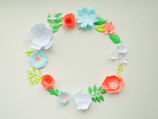 round frame with color paper flowers on the white stucco. Flat lay. Nature concept