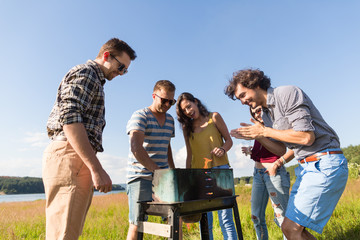 Young people having barbecue on field near lake