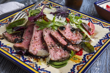 Traditionelles italienisches Tagliata Steak mit Parmesan und Salat als close-up auf einem Teller